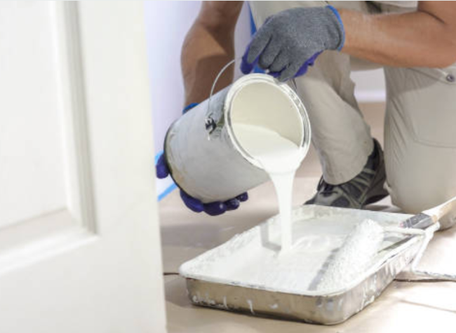 Man pouring paint into a paint pan.