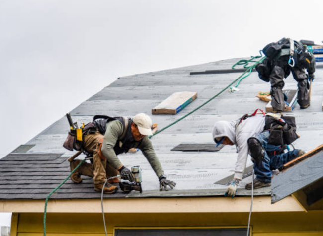 Group of roofers installing shingles on a house.